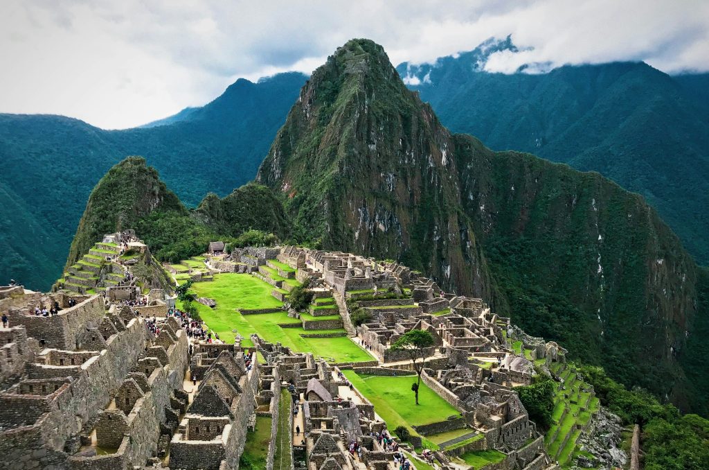 Een uitzicht op Machu Picchu met stenen terrassen en gebouwen tussen groene bergen.